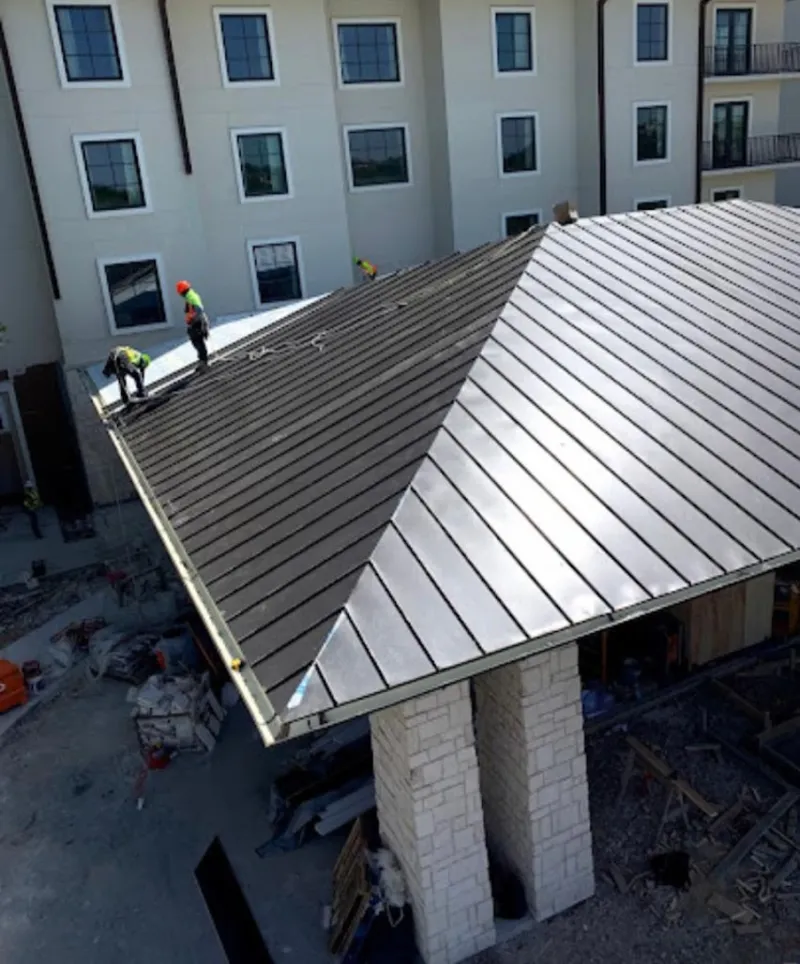 Crew installing standing seam metal roof panels on a commercial project in Marysville